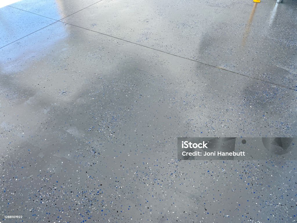 A freshly painted with a gray epoxy finish A freshly painted with a gray epoxy finish sprinkled with blue, black and white plastic chips. Flooring Stock Photo