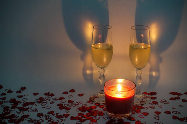 istock Two champagne glasses with a lit candle in front surrounded by heart shaped confetti 1288102026