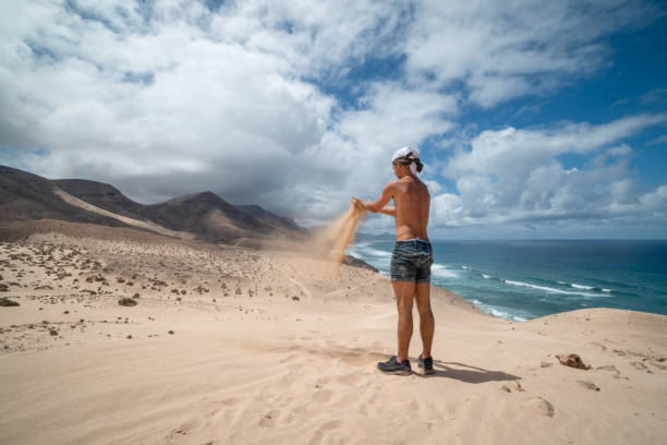 il giovane prende la sabbia tra le mani a jandia. fuerteventura. canarie - light sea low tide fuerteventura foto e immagini stock