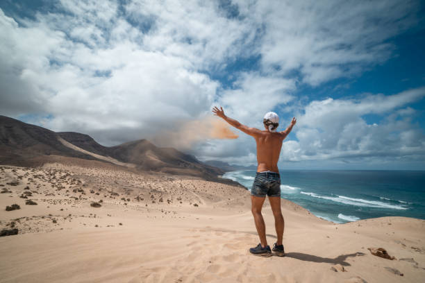 il giovane prende la sabbia tra le mani a jandia. fuerteventura. canarie - light sea low tide fuerteventura foto e immagini stock