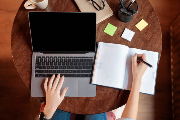 istock Lady sitting at desk using laptop with blank screen, mockup 1288104151