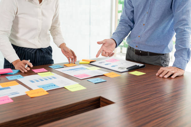 istock Creative group of business people brainstorming use sticky notes picking to share idea on table decision Choosing Concept for developing plan in business conference room 1288105840