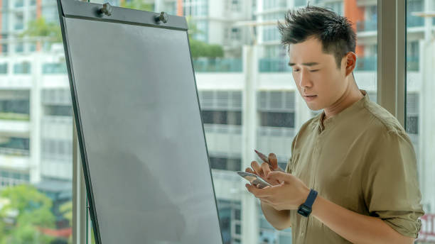 istock Serious Businessman Using Presentation Flipchart Stand Board in Office 1288105872