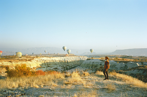 Young Caucasian man standing and looking at hot air balloons in  Cappadocia in Turkey
