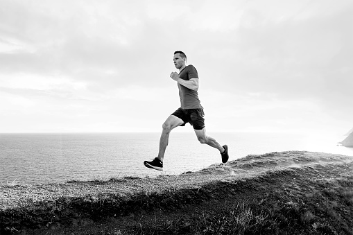 mature man athlete run on mountain trail black and white image