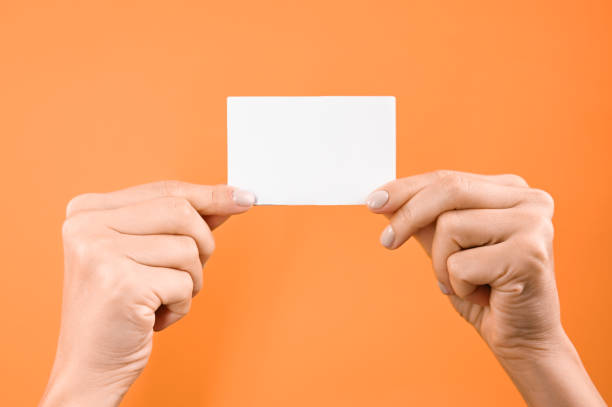 istock Hand holds white blank sign on orange background 1288119740