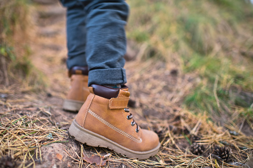 Suceesful woman hiker legs stand on mountain peak cliff edge