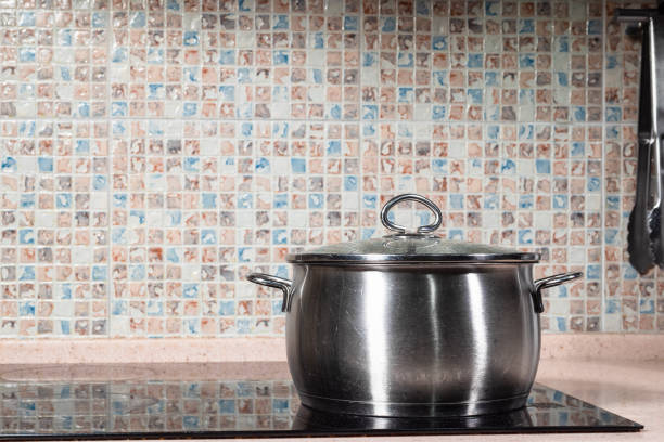 closed old steel stockpot on black ceramic stove in table at home kitchen