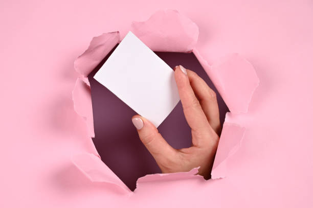 istock Hand holds a business card on a pink background 1288120628