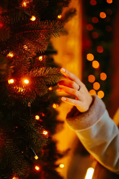 istock Woman's hand with christmas lights on the tree. 1288124697