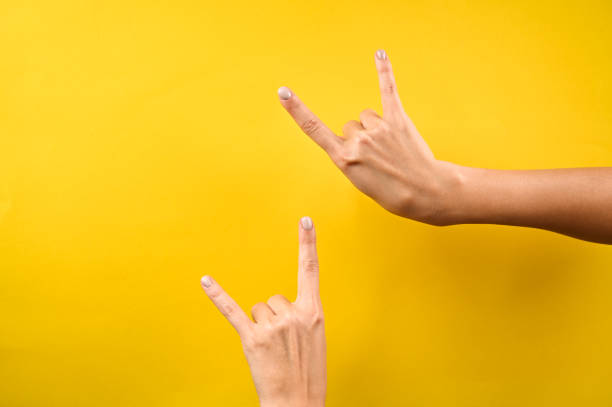 Woman's hand shows rock and roll hand signs isolated on yellow background. Horns sign Woman's hand shows rock and roll hand signs isolated on yellow background. Horns sign. High quality photo rocker nails stock pictures, royalty-free photos & images