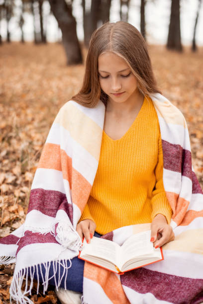 istock Young girl reading a book in a fall forest 1288125965