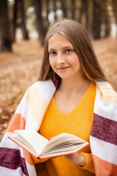 istock Charming young girl with a book in autumn forest. 1288125978