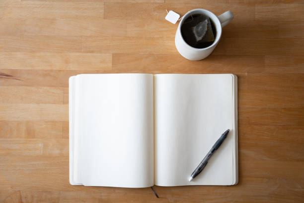 An open journal and pen on a table with a cup of tea for a mental health break. stock photo