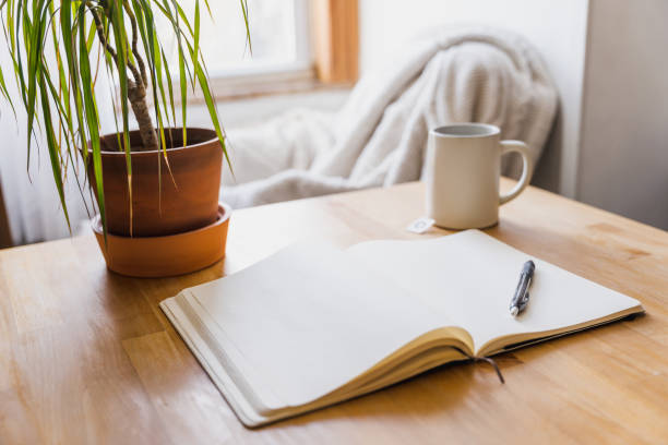 An open journal and pen on a table with a cup of tea for a mental health break. stock photo