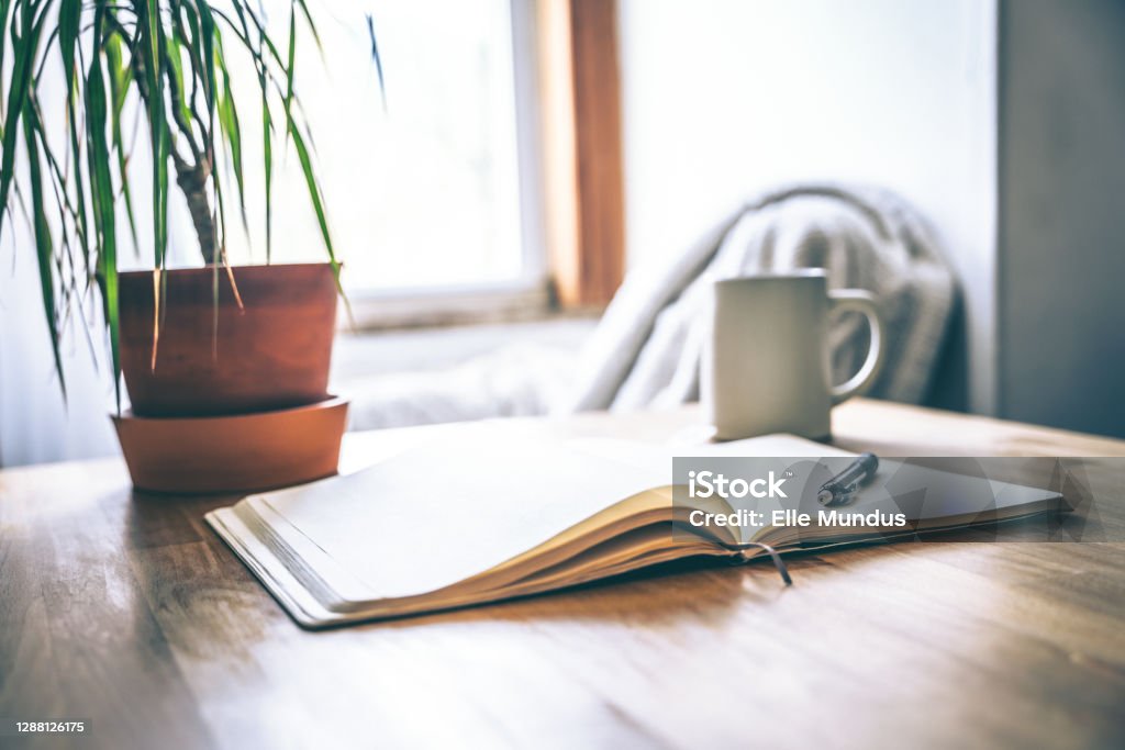 An open journal and pen on a table with a cup of tea for a mental health break. Self-care and mental health is vital, especially during difficult times. Taking a break to journal can help with stress. Diary Stock Photo