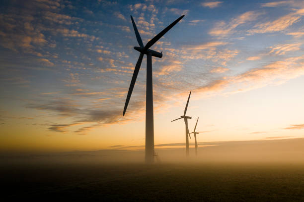 istock Three wind turbines at sunrise in fog 1288128458
