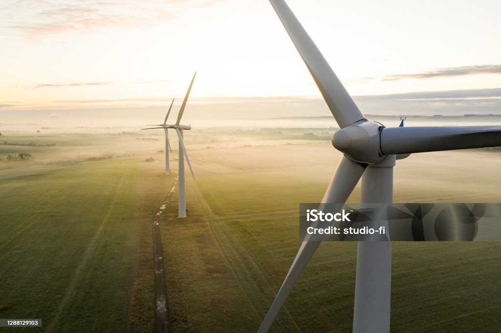 Three wind turbines at sunrise Aerial view of three wind turbines in the early morning fog at sunrise in the English countryside Wind Turbine Stock Photo