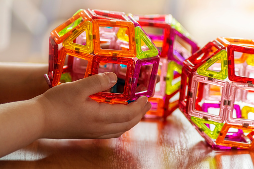 The child plays with a colorful magnetic constructor. Close-up. Ball.