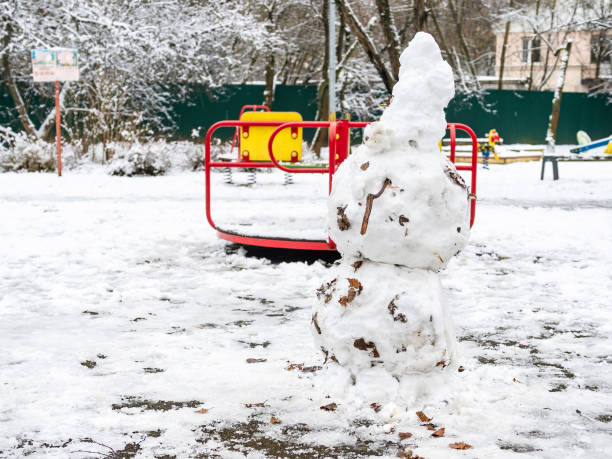 snowman made from first snow on playground - adhering imagens e fotografias de stock