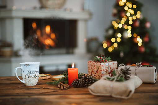 Christmas background on Christmas tree and fireplace in bokeh with wooden table on foreground.