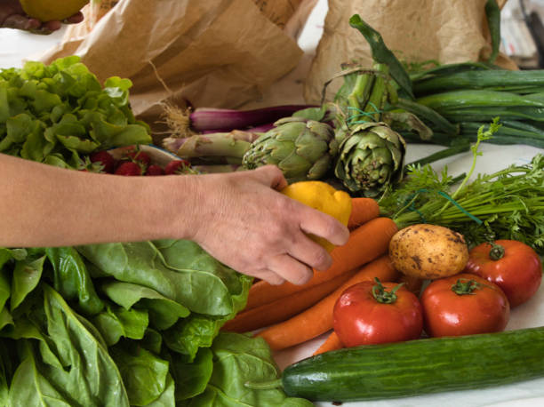 istock Assortment of vegetables placed on a table, with a female hand placing a lemon 1288131546