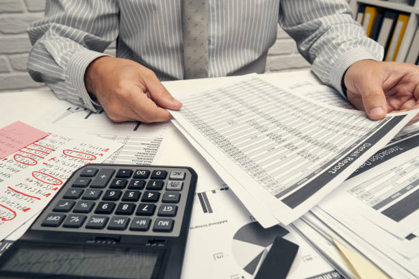 istock Business analysis and accounting concept - businessman working with document, spreadsheet, using calculator, tablet pc. Office desk closeup. 1288131585
