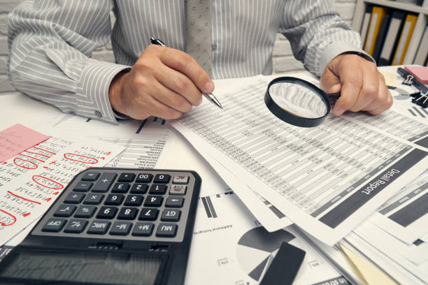 istock Business analysis and accounting concept - businessman working with document, spreadsheet, using calculator, tablet pc. Office desk closeup. 1288131638