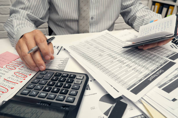 istock Business analysis and accounting concept - businessman working with document, spreadsheet, using calculator, tablet pc. Office desk closeup. 1288131704