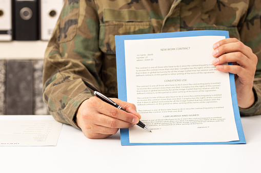 Close up of military man hands showing and pointing contract signature space in the academy
