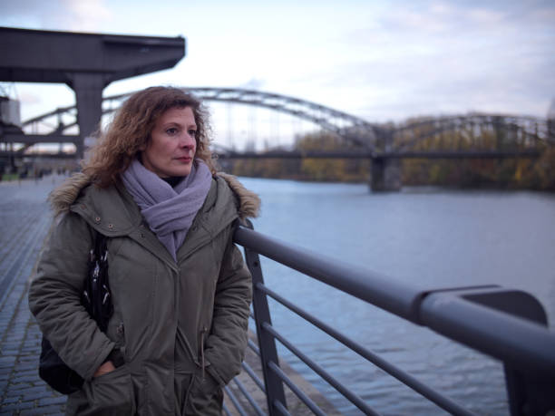 istock Woman deep in thought, stops next to a river and stares into distance. 1288133854
