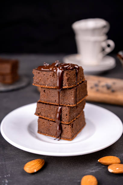 istock Cocoa brownies pouring with melted dark chocolate on a white plate. Black background 1288139367