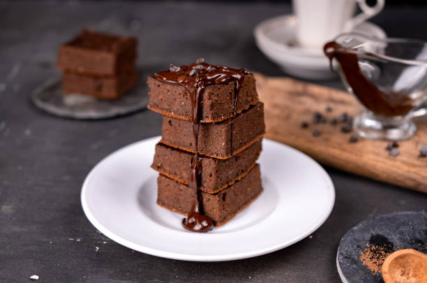 istock Cocoa brownies pouring with melted dark chocolate on a white plate. Black background 1288139450