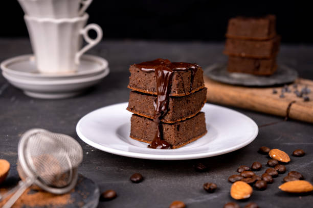 istock Cocoa brownies pouring with melted dark chocolate on a white plate. Black background 1288139481