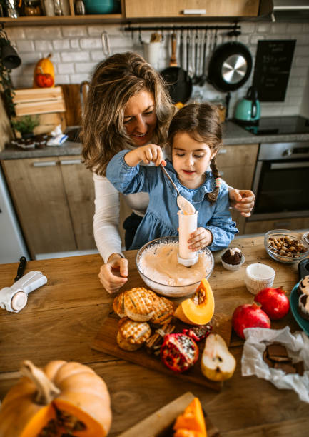 istock Mother and daughter baking and decorating cupcakes at home 1288140483