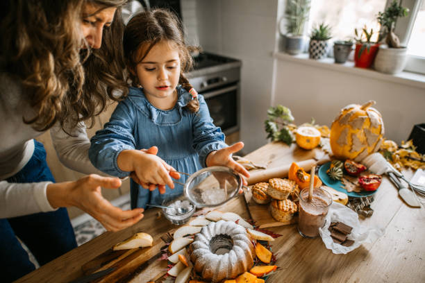istock Mother and daughter sprinkling icing sugar on cake 1288140651