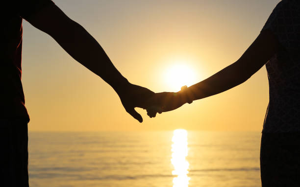 istock Silhouette of couple holding hands against the setting sun 1288143208
