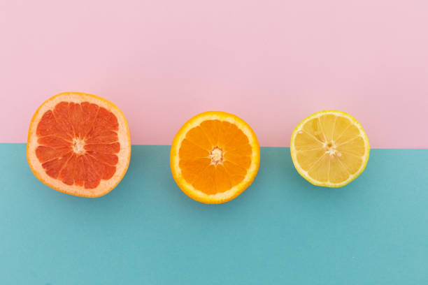 istock Grapefruit, orange and lemon halves on pink and blue background 1288143218