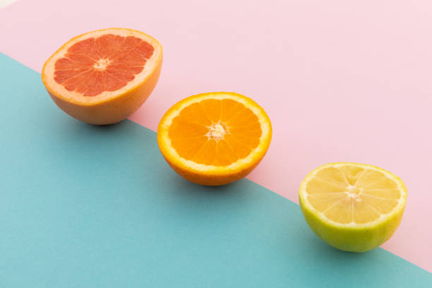 istock Grapefruit, orange and lemon halves on pink and blue background 1288143326