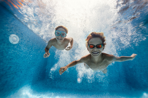Little boys are having fun swimming underwater in pool.\n\nNikon D850