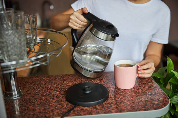 istock Person tilting a kettle with water over a teacup 1288148326