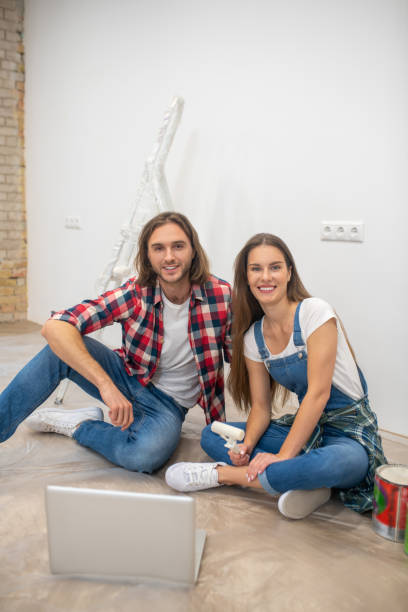 istock Young couple sitting on the floor and smiling 1288148611