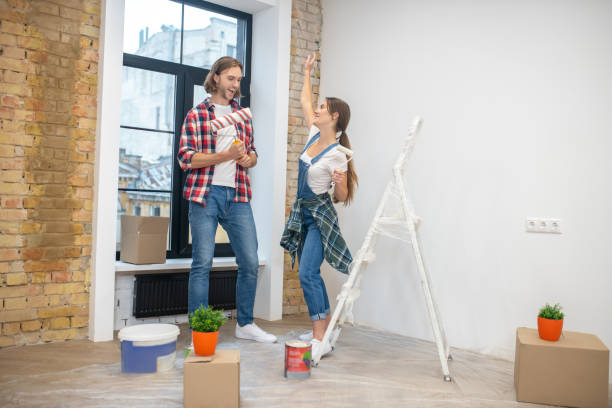 istock Young couple standing n in the empty room ready to start paintng 1288148635