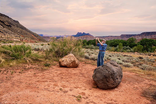 Senior man enjoying the scenery and taking a photograph at beautiful Zion National Park.