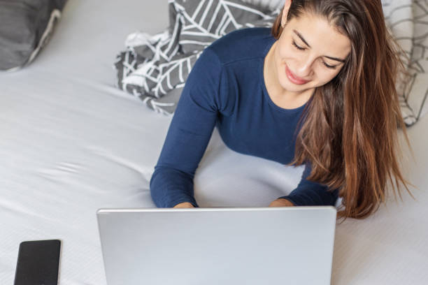 istock Young woman is using laptop in bed 1288155985