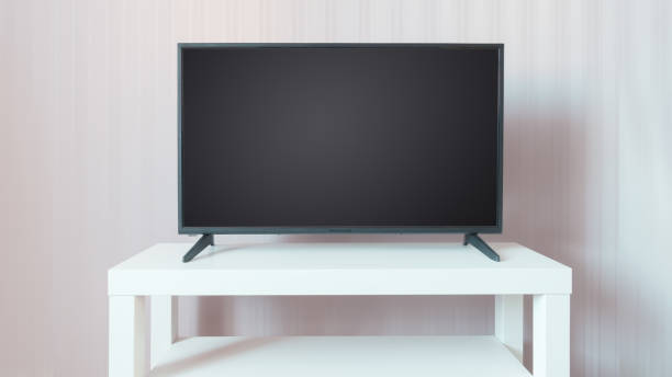 istock Black TV on a white stand against beige wall background 1288156101