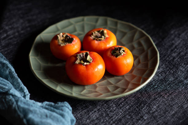 istock Persimmon orange kaki fruit on a rustic plate 1288156760
