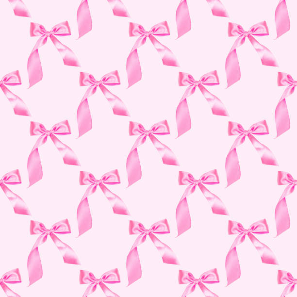 Pink tied bow seamless repeat symmetrical pattern on light rose color background.