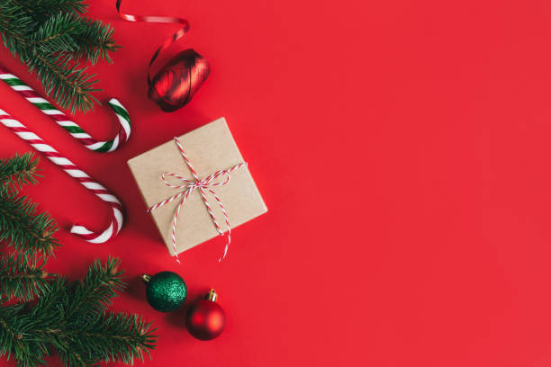 istock Gift box with spruce branches, balls and candy canes on a red background. 1288158962