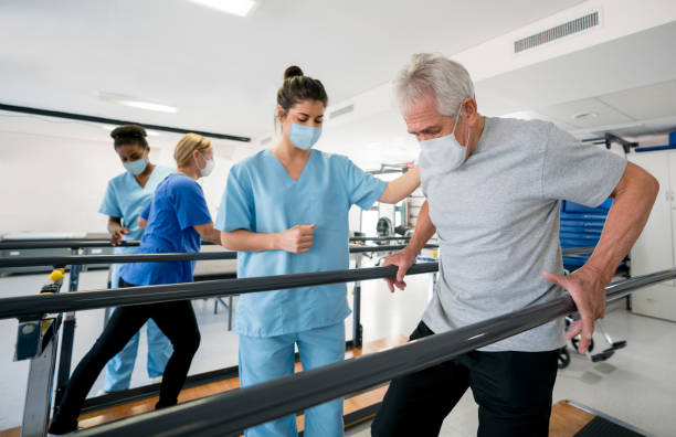 Group of doctors and patients in a rehab center wearing facemasks while doing their physiotherapy Group of doctors and patients in a rehab center wearing facemasks while doing their physiotherapy - COVID-19 pandemic lifestyle concepts physical therapy stock pictures, royalty-free photos & images